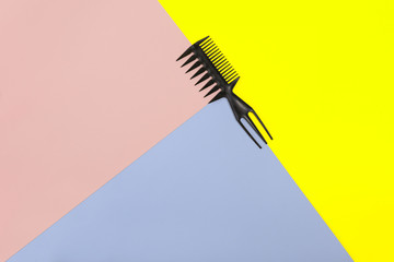 Comb on the color pink, yellow, blue paper background. Top view