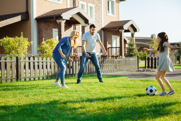 Little girl playing football with her parents
