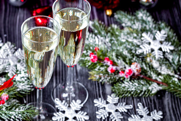 glasses of champagne and Christmas ornaments on dark wooden back