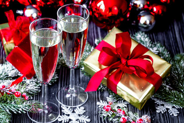 glasses of champagne and Christmas ornaments on dark wooden back