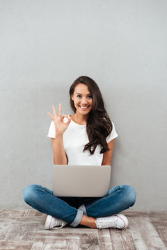 Cheerful young asian woman working on laptop computer