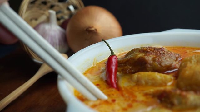 Using chopsticks to eat and taste thick curry noodle, Malaysian foods