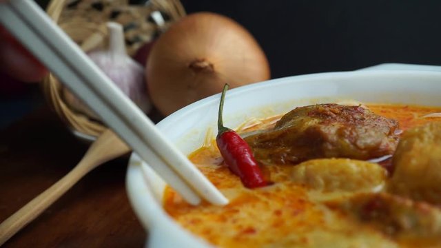 Using chopsticks to eat and taste thick curry noodle, Malaysian foods