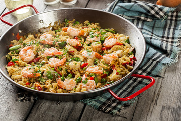 Traditional seafood paella with shrimp, fish and chicken seved in paellera