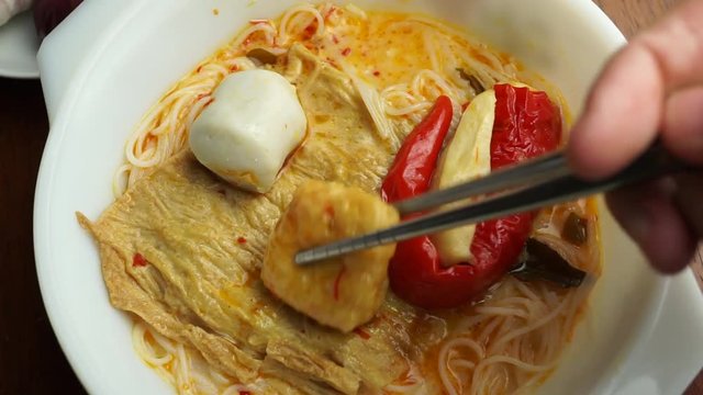Trying to use chopsticks to pick on ingredients inside curry noodle bowl, Malaysian foods