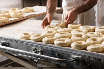 Baker preparing dough for bagels - obrazy, fototapety, plakaty