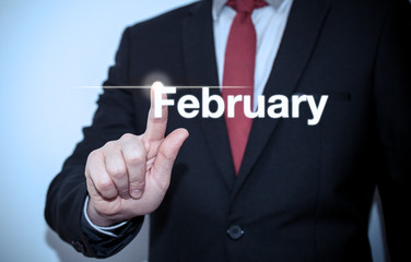 Businessman pressing button on virtual screen February button - concept