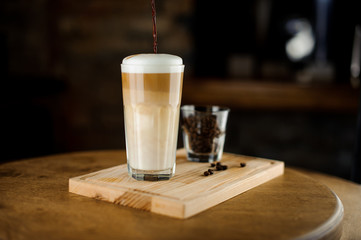 Hot latte coffee in a high glass cup on a wooden board