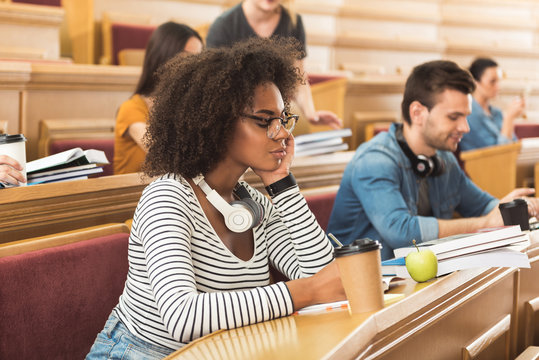 Serious girl making notes at lecture hall