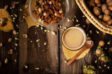 Healthy snack on rustic table indoors on autumn. Almonds and pistachio in bowl.