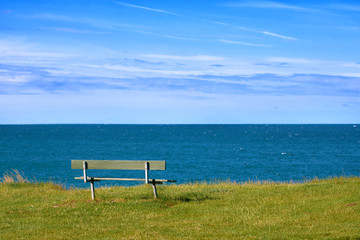 Empty bench on the shore of the ocean on a summer day