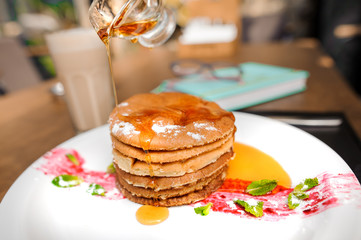 Delicious pancakes with honey on plate on table