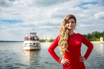 Fototapeta na wymiar pretty young woman in red near the lake in summer park