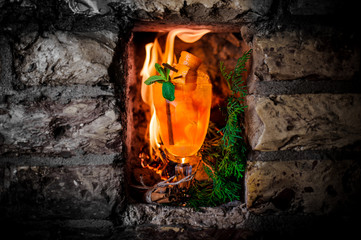 Hot orange drink against the background of a flame