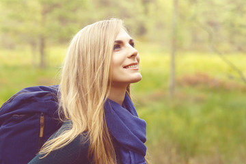 Close-up portrait of a happy, beautiful blond girl walking in forest and swamps. Camp, tourism, hiking concept.