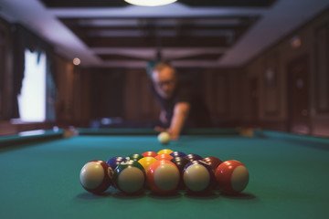 Young man playing billiard indoors. Spending free time on gambling