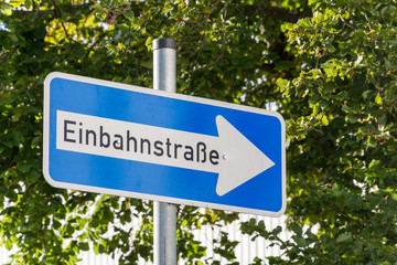 German One Way street sign with trees in the background