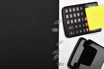Note paper, hole punch and paper clips on white surface