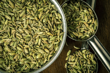 close up the fennel seed in  spoon on brown wooden table - obrazy, fototapety, plakaty