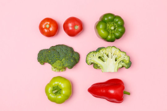 Top view of broccoli, green pepper, tomatoes, red paprika on a pastel pink background. Top view of seasonal vegetables. The concept of a healthy diet