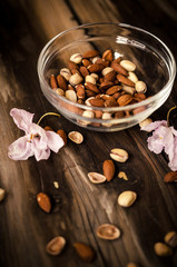 Healthy snack on rustic table indoors on autumn. Almonds and pistachio in bowl.