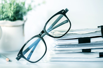 Close up black reading eyeglasses on the  stacking of office paper , business working document and information data concept. - obrazy, fototapety, plakaty