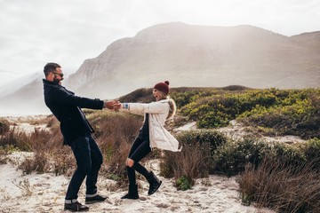 Beautiful couple dancing along the beach on winter day
