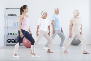Naklejka premium Elderly people exercising with trainer