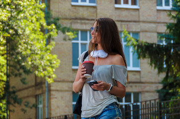 Beautiful stylish girl student drinking coffee on a city street