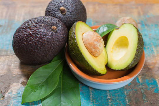 Ripe fresh avocado with leaves on blue wooden table