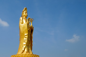 Chinese Goddess of compassion and mercy Guan Yin (Guan Yim). Standing statue which is famous in Chinese Buddhism and Zen, symbol of love and mercy, with blue sky background
