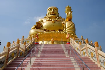 Poster Bouddha Sculpture assise du grand Bouddha doré, tenant des barres d& 39 or à la main, sur une colline en haut des escaliers avec fond de ciel en Thaïlande.