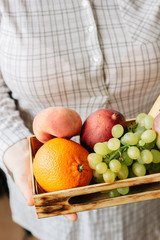 Woman holding box with fruits in hands.