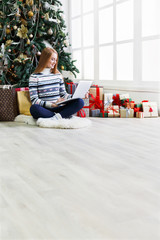 Young woman shopping online in cozy christmas interior