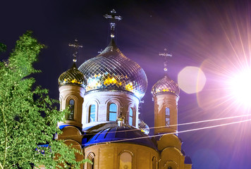 The Church of THE HOLY APOSTLES AND THE GOSPEL JOHN OF BOGHOSLOV in the park at autumn night. Pokrov town, Ukraine, 2017. Lighted golden domes