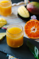 Fresh mango and orange detox drink over black slate.