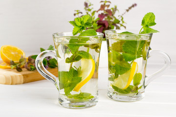 Two glass cups fresh mint tea with lemon and a bunch of mint in vase