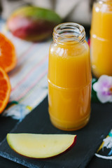 Mango and orange smoothie in transparent bottle.