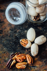 Pecan nuts inside glass jar on rustic surface.