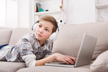 Teenage boy in headphones with laptop at home
