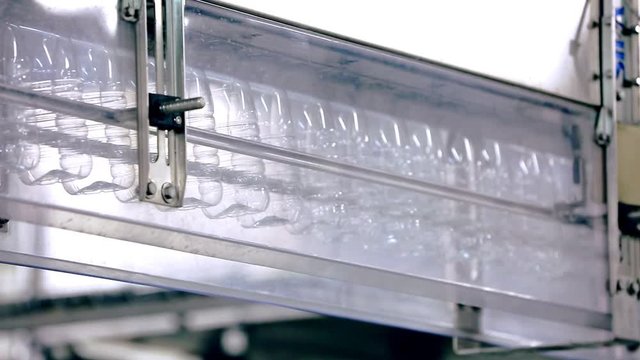Empty plastic bottle on conveyor line. Bottle production line. Plastic bottles for liquid products on conveyor belt. Milk bottles moving on manufacturing line. Food industry