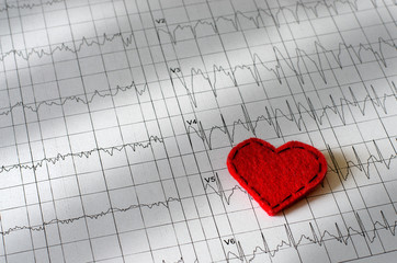 Electrocardiogram on paper.  Red heart made of fabric