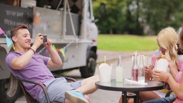 man taking video of friends eating at food truck