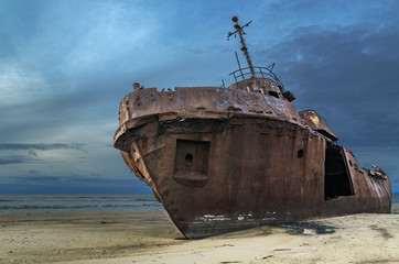 Een oud verwoest schip ligt te roesten aan de kust.