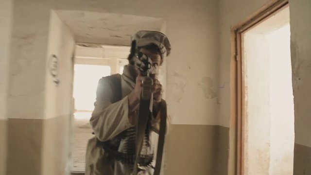 Armed man aims at the enemy in the corridor of the abandoned building