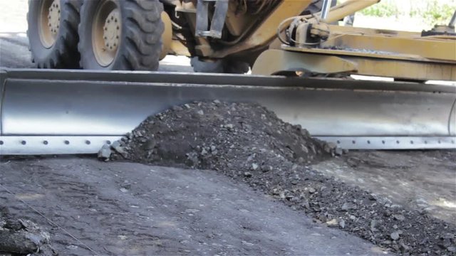 grader clears the road/An industrial grader unfolds old asphalt on the road