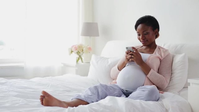 happy pregnant woman with smartphone at home