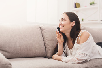 Young girl talking on mobile lying on sofa