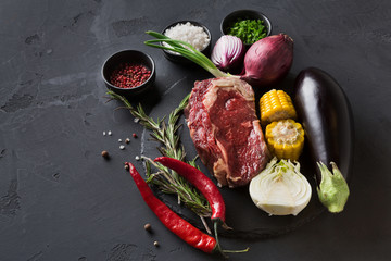 Rib eye steak and vegetables on plate at black background