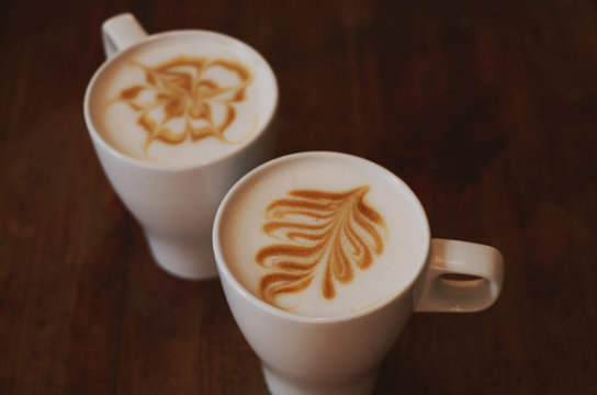 Two cups of latte on brown wooden table